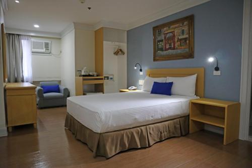 馬尼拉的住宿－奎松市馬勒卡費薩爾酒店，酒店客房带一张大床和一把椅子