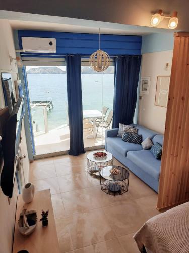 a living room with a blue couch and a view of the ocean at Mpitzarakis Studio On the Beach in Agia Pelagia