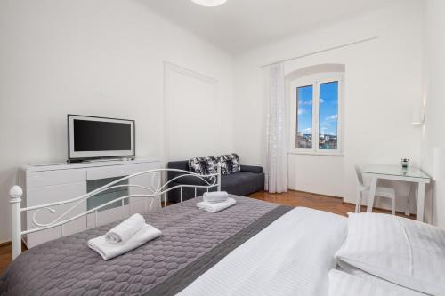 a white bedroom with a bed and a tv at Apartment Dana in Rijeka