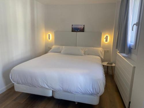 a white bed in a small room with a window at APARTAMENTOS ARATUSTE - News a estrenar in Mundaka