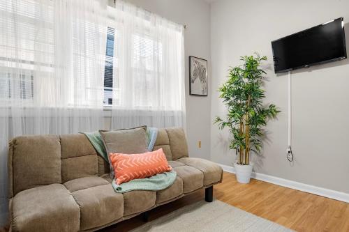 een woonkamer met een bank en een flatscreen-tv bij Cozy 1BR Unit in Prime Location - Perfect for Solo Travelers or Couples! in Hounslow