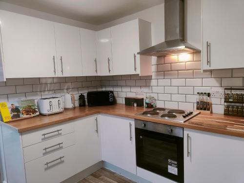 a kitchen with white cabinets and a stove top oven at Cosy Home in Historical Beverley Town with Parking in Beverley