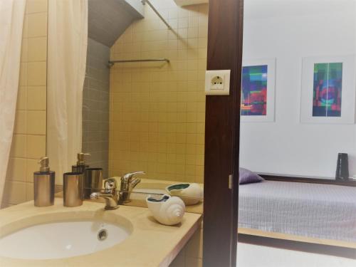 łazienka z umywalką i łóżkiem w obiekcie Troia MaisMais apartamento w mieście Troia