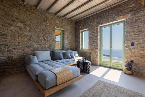 a living room with a couch and a stone wall at Kalma Living Luxury Villas in Kithnos
