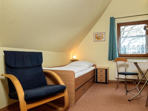 ein Schlafzimmer mit einem Bett, einem Stuhl und einem Schreibtisch in der Unterkunft Reethus Blinkfüer in Timmendorf