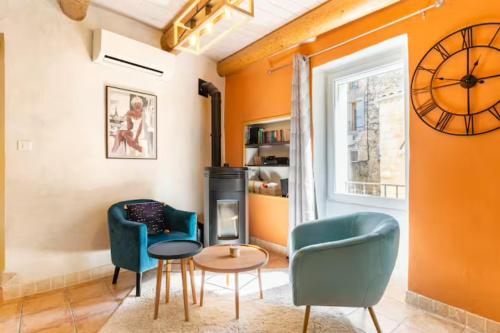 a living room with two chairs and a table and a clock at La Parenthèse, chambres d'hôtes in Rochegude-Drome