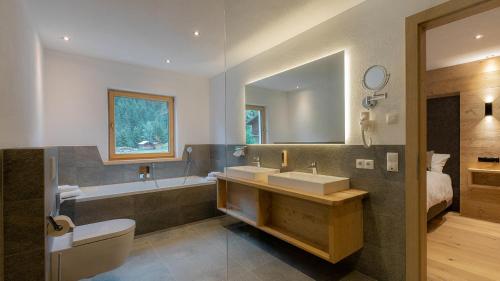 a bathroom with two sinks and a tub and a toilet at das Chaletdorf - Pitztal in Sankt Leonhard im Pitztal