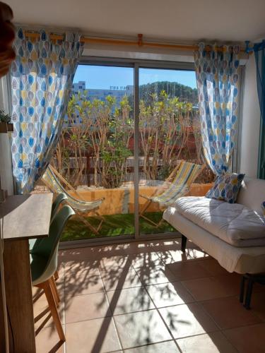 ein Wohnzimmer mit einem Sofa und einem großen Fenster in der Unterkunft Appartement en Résidence avec piscine proche mer in Le Barcarès