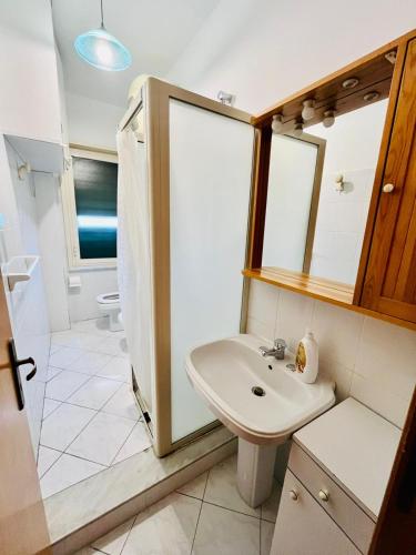 La salle de bains blanche est pourvue d'un lavabo et d'un miroir. dans l'établissement Residence Sileno Beach Giardini Naxos, à Giardini Naxos