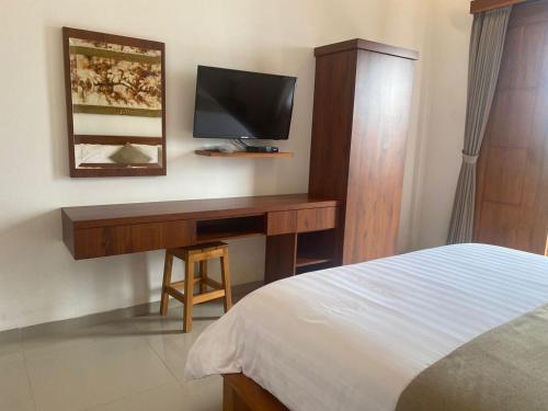 a bedroom with a desk with a tv and a bed at D'TRANSIT in Nusa Penida