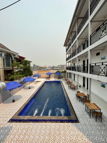 uma piscina com mesas e guarda-sóis num edifício em Vang Vieng Backpackers Hostel em Vang Vieng