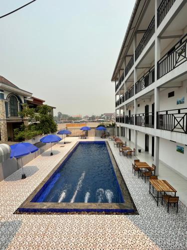 萬榮的住宿－Vang Vieng Backpackers Hostel，大楼内带桌子和遮阳伞的游泳池
