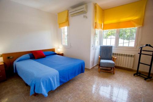 a bedroom with a blue bed and a chair at Catalunya Casas Nature & Tranquility only 25kms from Barcelona in Torrelles de Llobregat