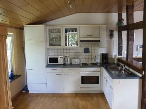 een keuken met witte kasten, een wastafel en een magnetron bij Ferienwohnung Drewitz in Schmallenberg