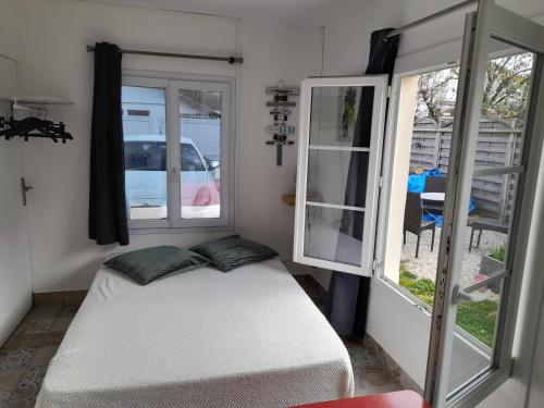 een kleine slaapkamer met een bed en 2 ramen bij LA DATCHA in Saujon