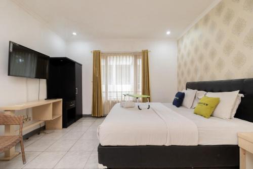 een slaapkamer met een groot bed met gele kussens bij Urbanview Hotel Gunung Geulis Village by RedDoorz in Bogor
