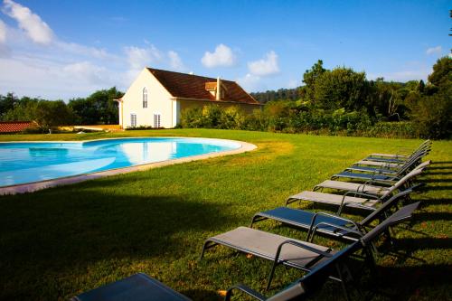 a row of lawn chairs next to a swimming pool at Quinta da Nasce Água in Angra do Heroísmo