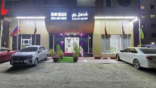 two cars parked in a parking lot in front of a building at Ruwi Beach Hotel Apartments - MAHA HOSPITALITY GROUP in Sharjah
