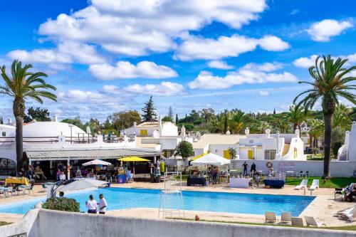 a pool at a resort with palm trees and buildings at Villa PACA Algarve Vilamoura 8 personnes in Quarteira