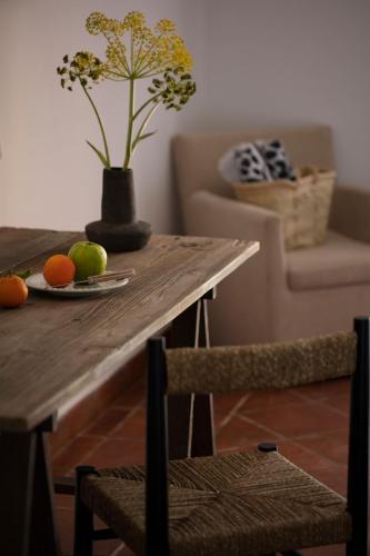 a table with a plate of fruit and a vase with flowers at Can Arabí - Adults Only in Ibiza Town