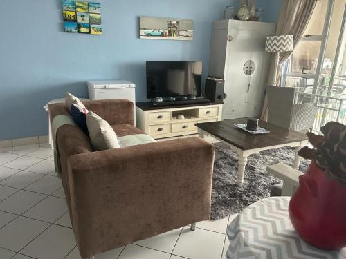 a living room with a couch and a tv at 205 Laguna lacrete in Uvongo Beach