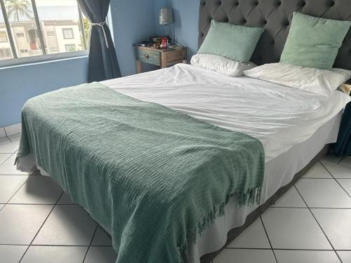 a large bed with a green blanket on it at 205 Laguna lacrete in Uvongo Beach
