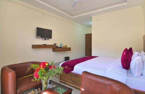 a bedroom with a bed and a couch and a tv at LA Riqueza Dhanolti View # Mountain View Rooms # Parking # Lift # Near to Eco Park & Surkanda Devi Temple in Dhanaulti