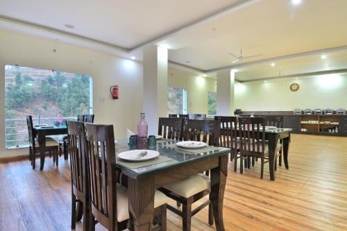 a dining room with a table and some chairs at LA Riqueza Dhanolti View # Mountain View Rooms # Parking # Lift # Near to Eco Park & Surkanda Devi Temple in Dhanaulti