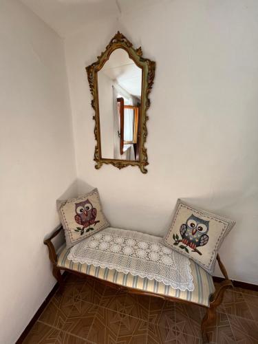 a mirror and a bench with pillows in a room at Casina Orione in Montecatini Val di Cecina
