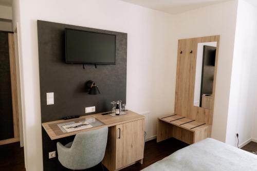 a room with a desk and a television on a wall at Hotel am Fluss in Neuburg an der Donau