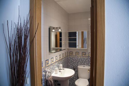 W łazience znajduje się umywalka, toaleta i lustro. w obiekcie Flat with parking in the center of Las Rozas w mieście Las Rozas de Madrid