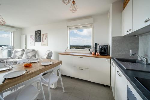 une cuisine avec des placards blancs et une table avec des chaises dans l'établissement Large and bright nest with a clear view of the sea, à Montpellier