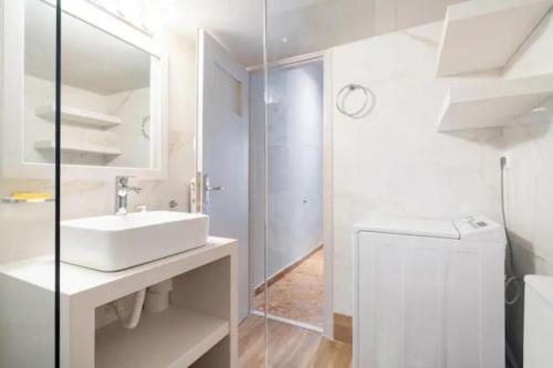 a white bathroom with a sink and a mirror at Flisvos Marina refurbished apartment in Athens