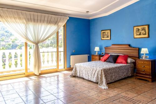 a blue bedroom with a bed and a large window at Catalunya Casas Spacious, Sublime Villa just 15km to Barcelona! in Torrelles de Llobregat