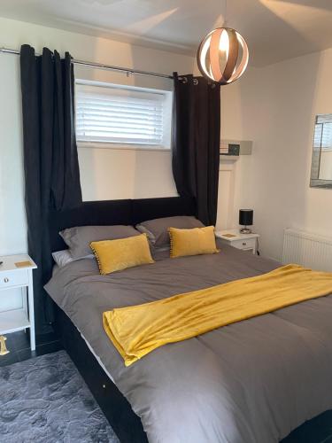 a bedroom with a bed with a black headboard and yellow pillows at Katy’s Cwtch in Cardigan