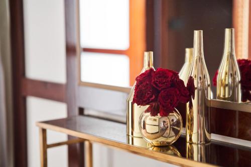a table with two vases with red roses in them at Portrait Milano - Lungarno Collection in Milan