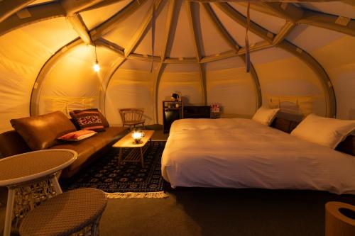 淡路市にあるピクニックガーデンのベッド1台とテント内のソファが備わる客室です。