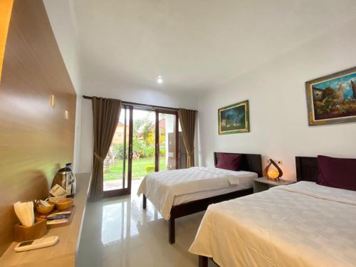 a hotel room with two beds and a window at Padang-Padang Sari Homestay in Uluwatu