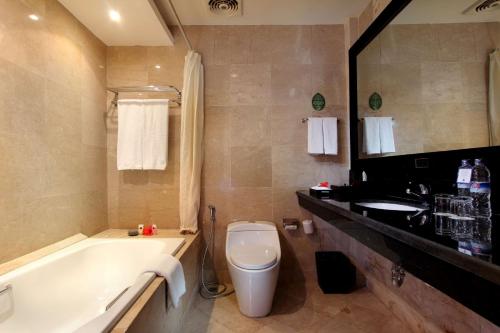 a bathroom with a tub and a toilet and a sink at Best Western Resort Kuta in Kuta