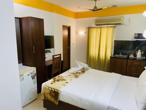 a bedroom with a bed and a desk and a kitchen at Hotel Signature Cochin in Cochin