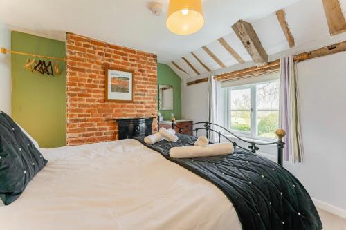 1 dormitorio con 1 cama grande y pared de ladrillo en Bar Lane Cottage - Norfolk Cottage Agency en Reepham