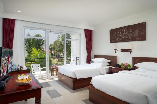 a hotel room with two beds and a balcony at Sala Siem Reap Hotel in Siem Reap