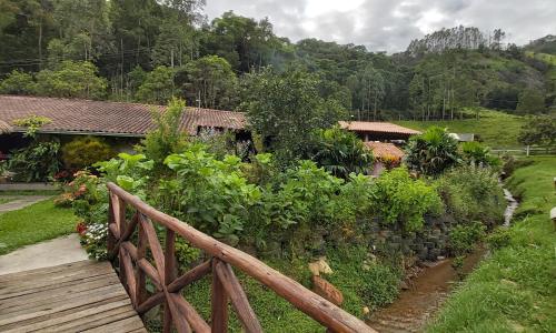 een houten brug over een tuin met bloemen en planten bij Solo Sagrado in Bom Jardim