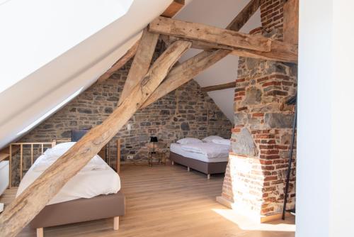 een slaapkamer met 2 bedden en een bakstenen muur bij Maison de vacances Le Vieux Marronnier in Dinant