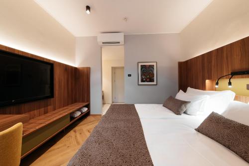 a hotel room with a large bed and a flat screen tv at Hotel Švicarija - Terme Dobrna in Dobrna