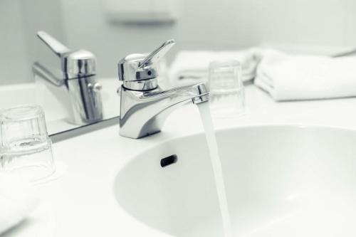 ein Waschbecken mit Wasser aus einem Wasserhahn in der Unterkunft Golden Tulip Luebecker Hof in Lübeck