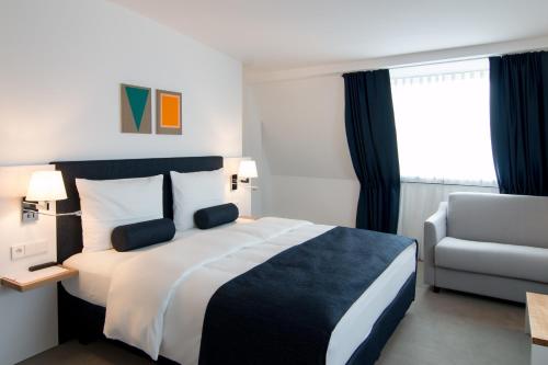 a hotel room with a bed and a chair at Bayer 89 Vi Vadi Hotel in Munich