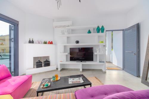 a living room with pink furniture and a tv at Mythos Luxury Villa-Skiathos in Troulos