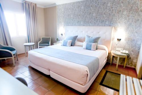 ein Schlafzimmer mit einem großen weißen Bett mit blauen Kissen in der Unterkunft Alborán Algeciras in Algeciras