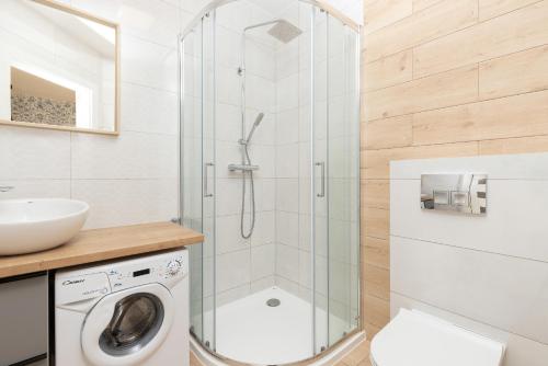 a shower in a bathroom with a washing machine at Liliowa Seaside Apartments by Renters in Dębki